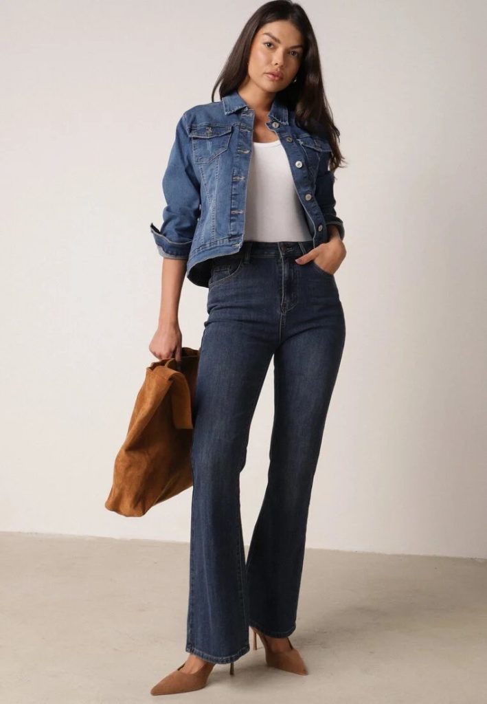 Stylizacja z jeansami bootcut (dzwony, flare), jeansową kurtką, zamszową torebką slouchy, zamszowymi szpilkami i białym topem.